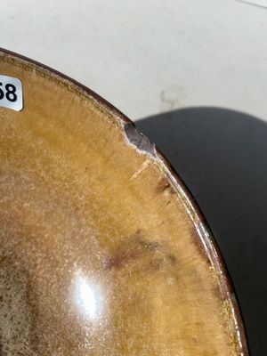 Sale Photo Thumbnail #62: Large wheel-thrown studio art pottery bowl featuring a ribbed exterior with dark olive green glaze and a warm tan-gold glazed interior. Signed 'Pask 83' (or similar artist signature) on the unglazed foot ring base. Dated 1983. Shows a small chip along the