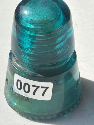 Sale Photo Thumbnail #99: Vintage teal/aqua green glass insulator, embossed with 'HEMINGRAY' and 'MADE IN U.S.A.' along the base with a sharp drip edge. Shows typical minor surface wear, overall good condition.