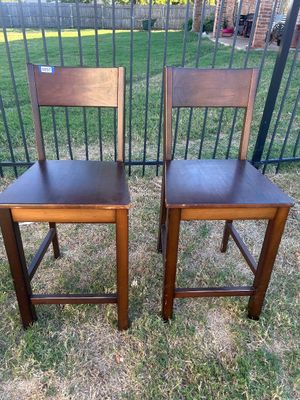 Sale Photo Thumbnail #58: A matching pair of dark stained wood counter-height stools or high-seat chairs featuring straight backs and square stretchers for footrests. Both pieces show light edge wear and scuffs consistent with use.
