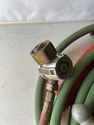 Sale Photo Thumbnail #84: Assorted oxy-acetylene welding/brazing hoses and a red Turbo-Torch handle featuring brass fittings, valve adjustments, and connection couplers. Show signs of age and wear consistent with previous shop or job-site use.