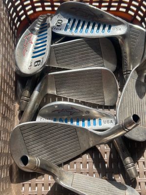 Sale Photo Thumbnail #111: A collection of vintage golf iron club heads including Simmons Tiger Shark USA models (3-iron, 8-iron, 9-iron, and others). Metal construction with signature blue cavity slot fill and etched shark logo details. Heads show play wear and surface patina typi