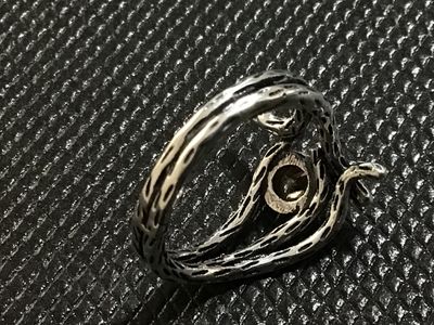 Sale Photo Thumbnail #34: A silver-tone statement ring featuring a textured, branch-like motif wrapping around a bezel-set amber/citrine-colored faceted stone. Measured on a ring mandrel, it fits approximately at size 7.5. Good condition with light wear.