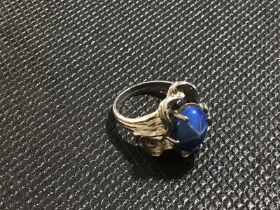 Sale Photo Thumbnail #133: Vintage statement ring featuring an oval cabochon blue star sapphire (asterism evident) set in an ornate, textured white gold mounting. Stamped '' inside the band alongside a maker's mark. Ring size measures approximately 5.5 - 5.75 on mandrel. Pre-owned 