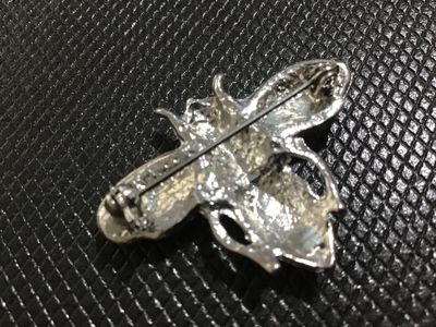 Sale Photo Thumbnail #109: Silver-tone metal insect brooch featuring vibrant red, black, teal, and green enamel detailing on the body and wings. Features a rollover safety clasp pin back. Good condition with minimal wear visible on the finish.
