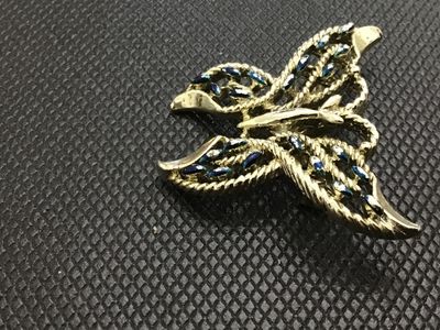 Sale Photo Thumbnail #23: A vintage gold-tone metal butterfly brooch featuring textured rope-like openwork wings accented with blue painted highlights. Includes a standard roll-over safety clasp pin mechanism on the back. Shows light surface wear consistent with age.