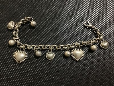 Sale Photo Thumbnail #117: Silver-tone metal chain charm bracelet featuring puffy heart charms with textured borders alternating with smooth spherical bead charms. Includes a lobster claw clasp. Shows slight surface patina and minor wear consistent with use. Overall good condition.