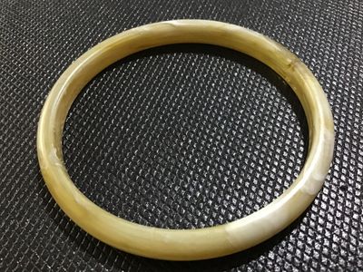 Sale Photo Thumbnail #39: A vintage slip-on bangle bracelet crafted from marbled cream and yellow translucent resin or lucite with swirled white accents. Smooth polished surface with no visible cracks or heavy damage.