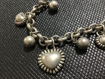 Sale Photo Thumbnail #118: Silver-tone metal chain charm bracelet featuring puffy heart charms with textured borders alternating with smooth spherical bead charms. Includes a lobster claw clasp. Shows slight surface patina and minor wear consistent with use. Overall good condition.