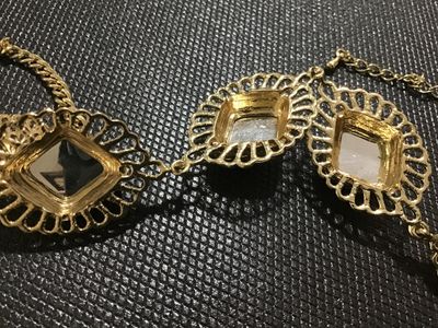 Sale Photo Thumbnail #122: Gold-tone metal statement necklace featuring three large, faceted emerald-green faux gemstone panels set in filigree frames, flanked by openwork round filigree accents. Includes an adjustable chain link with a lobster claw clasp. Appears to be in good pre