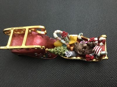 Sale Photo Thumbnail #13: Decorative enameled metal hinged trinket box shaped like a Christmas sleigh filled with toys, a teddy bear, presents, candy canes, and a Christmas tree. Features rhinestone accents along the rim, gold-tone metal runners, magnetic closure, and a painted en