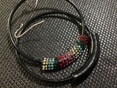 Sale Photo Thumbnail #80: Pair of thin black hoop drop earrings featuring curved bar sections set with colorful pavé rhinestones in shades of red, pink, green, blue, yellow, and clear. Fitted with silver-tone wire French ear hooks. In good pre-owned condition with all rhinestones