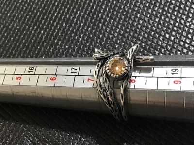 Sale Photo Thumbnail #33: A silver-tone statement ring featuring a textured, branch-like motif wrapping around a bezel-set amber/citrine-colored faceted stone. Measured on a ring mandrel, it fits approximately at size 7.5. Good condition with light wear.