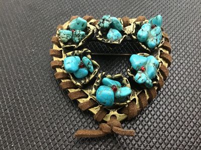 Sale Photo Thumbnail #15: Southwestern style heart-shaped brooch featuring brass-tone metal wrapped with brown suede cord trim. Decorated with clusters of faux turquoise stones accented with small red rhinestones. Includes a standard rollover safety clasp pin back. Good vintage co