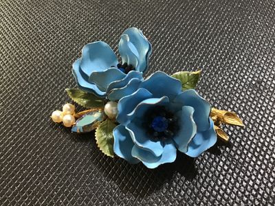 Sale Photo Thumbnail #86: A vintage Weiss gold-tone floral brooch featuring two light blue enameled flowers with blue rhinestone centers, faux pearl accents, a navette aurora borealis rhinestone, and green enamel leaves. Marked '© WEISS' on the back frame. Pin mechanism is intact