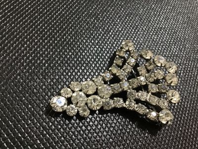 Sale Photo Thumbnail #32: Vintage silver-tone metal and clear rhinestone fan spray brooch. Features prong-set and channel-set faceted glass rhinestones arranged in a tiered, spreading fan design with a rollover safety clasp on the back. Showcases minor light surface wear and sligh