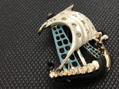 Sale Photo Thumbnail #25: Vintage nautical sailing ship brooch pin featuring white, light blue, and black enamel accents with clear rhinestone details set in gold-tone metal. Standard pin stem and safety clasp on the reverse. Shows minor wear to the enamel and finish consistent wi