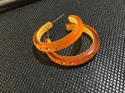Sale Photo Thumbnail #96: Pair of translucent orange acrylic or resin hoop pierced earrings featuring a yellow inner lining and clear rhinestones set around the outer edge. Pierced post backs. Good pre-owned condition with minor signs of wear.