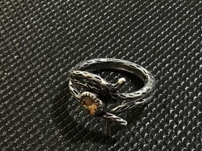 Sale Photo Thumbnail #35: A silver-tone statement ring featuring a textured, branch-like motif wrapping around a bezel-set amber/citrine-colored faceted stone. Measured on a ring mandrel, it fits approximately at size 7.5. Good condition with light wear.