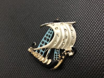 Sale Photo Thumbnail #28: Vintage nautical sailing ship brooch pin featuring white, light blue, and black enamel accents with clear rhinestone details set in gold-tone metal. Standard pin stem and safety clasp on the reverse. Shows minor wear to the enamel and finish consistent wi