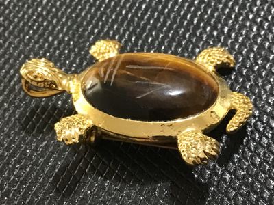 Sale Photo Thumbnail #62: Gold-tone turtle motif pin/brooch featuring a carved or etched tiger's eye cabochon shell. Includes a bail on the back so it can also be worn as a necklace pendant. Gold finish shows light surface wear/aging. Pin mechanism on back is intact and functional