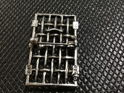 Sale Photo Thumbnail #42: A unique vintage pewter brooch pin designed as a jail door/gate with bars, hinges, and a padlock with chain detail across the front. The back is marked with "NWP" and copyrighted "© 1977". Features a standard rollover safety clasp pin back. Good vintage 