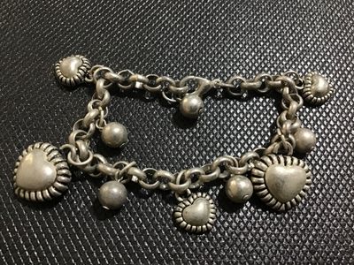 Sale Photo Thumbnail #119: Silver-tone metal chain charm bracelet featuring puffy heart charms with textured borders alternating with smooth spherical bead charms. Includes a lobster claw clasp. Shows slight surface patina and minor wear consistent with use. Overall good condition.
