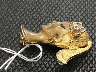 Sale Photo Thumbnail #3: Vintage Crown Trifari gold-tone costume jewelry brooch depicting a stylized woman's bust or head with a ponytail, painted black eyes, and a floral hair piece set with iridescent rhinestones. Marked on the back with the Crown Trifari logo. Pin mechanism is