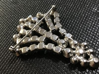 Sale Photo Thumbnail #30: Vintage silver-tone metal and clear rhinestone fan spray brooch. Features prong-set and channel-set faceted glass rhinestones arranged in a tiered, spreading fan design with a rollover safety clasp on the back. Showcases minor light surface wear and sligh
