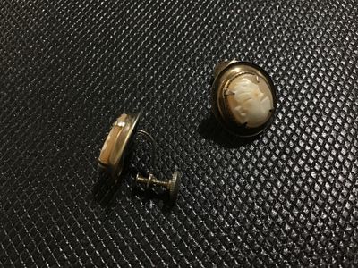 Sale Photo Thumbnail #128: Pair of vintage oval shell cameo earrings featuring carved female profile portraits set in gold-tone metal frames with screw-back closures for non-pierced ears. Good vintage condition with light wear consistent with age.