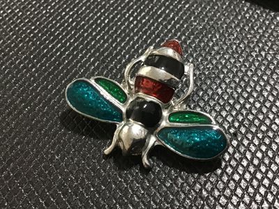 Sale Photo Thumbnail #108: Silver-tone metal insect brooch featuring vibrant red, black, teal, and green enamel detailing on the body and wings. Features a rollover safety clasp pin back. Good condition with minimal wear visible on the finish.