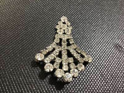 Sale Photo Thumbnail #31: Vintage silver-tone metal and clear rhinestone fan spray brooch. Features prong-set and channel-set faceted glass rhinestones arranged in a tiered, spreading fan design with a rollover safety clasp on the back. Showcases minor light surface wear and sligh
