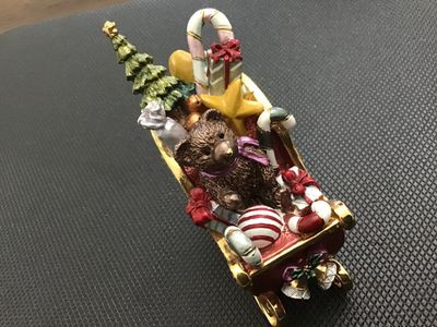 Sale Photo Thumbnail #9: Decorative enameled metal hinged trinket box shaped like a Christmas sleigh filled with toys, a teddy bear, presents, candy canes, and a Christmas tree. Features rhinestone accents along the rim, gold-tone metal runners, magnetic closure, and a painted en