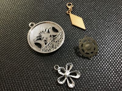 Sale Photo Thumbnail #78: A collection of 4 modern costume jewelry charms and pendants. Includes a silver-tone Celtic triple moon and pentagram pendant, a gold-tone glittery diamond-shaped charm with a lobster clasp, a silver-tone flower-shaped charm with a central crystal accent,
