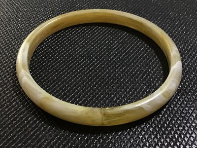 Sale Photo Thumbnail #40: A vintage slip-on bangle bracelet crafted from marbled cream and yellow translucent resin or lucite with swirled white accents. Smooth polished surface with no visible cracks or heavy damage.