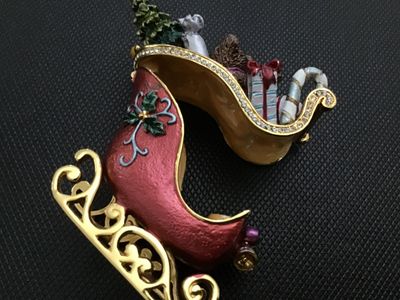 Sale Photo Thumbnail #14: Decorative enameled metal hinged trinket box shaped like a Christmas sleigh filled with toys, a teddy bear, presents, candy canes, and a Christmas tree. Features rhinestone accents along the rim, gold-tone metal runners, magnetic closure, and a painted en