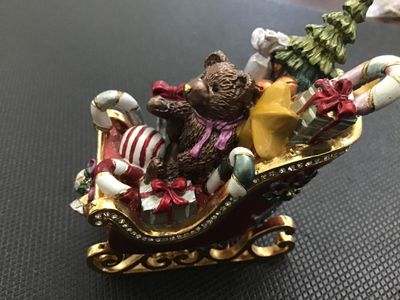 Sale Photo Thumbnail #10: Decorative enameled metal hinged trinket box shaped like a Christmas sleigh filled with toys, a teddy bear, presents, candy canes, and a Christmas tree. Features rhinestone accents along the rim, gold-tone metal runners, magnetic closure, and a painted en