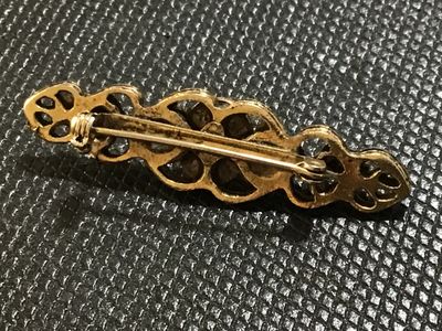 Sale Photo Thumbnail #76: Vintage gold-tone bar brooch featuring intricate filigree openwork design. Includes a standard pin back with c-clasp fastener. Shows light age-appropriate patina and surface tarnish on the reverse.