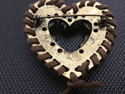 Sale Photo Thumbnail #16: Southwestern style heart-shaped brooch featuring brass-tone metal wrapped with brown suede cord trim. Decorated with clusters of faux turquoise stones accented with small red rhinestones. Includes a standard rollover safety clasp pin back. Good vintage co
