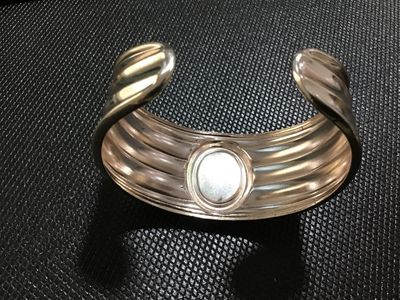 Sale Photo Thumbnail #102: Silver-tone wide ribbed cuff bracelet featuring a central bezel-set oval stone or cabochon accent in a light cream tone. Shows light surface wear and minor tarnishing consistent with pre-owned condition.