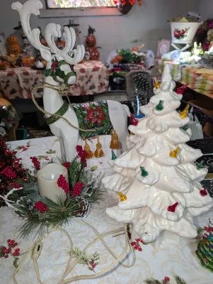 Sale Photo Thumbnail #57: Vintage white ceramic Christmas tree with colorful plastic bulbs, paired with a standing white reindeer figurine wearing a poinsettia saddle.