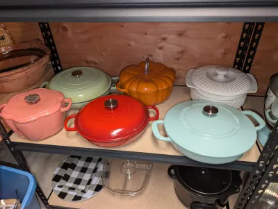 Sale Photo Thumbnail #14: Colorful enamel cast iron Dutch ovens and covered casseroles, including specialty flower and pumpkin-shaped pieces.