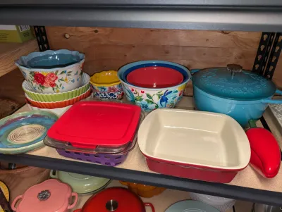 Sale Photo Thumbnail #16: Pioneer Woman and colorful ceramic kitchenware, including nesting mixing bowls, a Dutch oven, and baking dishes.