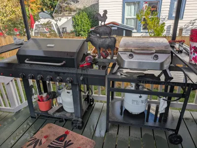 Sale Photo Thumbnail #31: Two outdoor propane grills, including a large black Master Cook 6-burner grill and a portable stainless steel Nexgrill mounted on a cart.