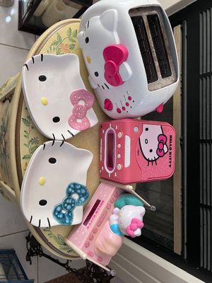 Sale Photo Thumbnail #7: Collection of Hello Kitty themed household goods, including a white 2-slice toaster, two ceramic face plates with bows, and two pink alarm clocks.