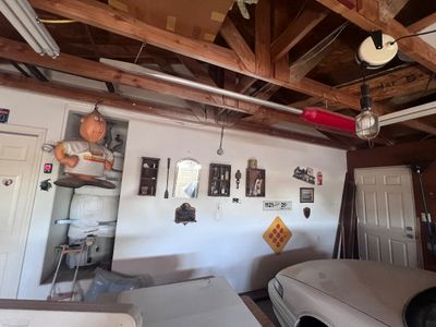 Sale Photo Thumbnail #17: Garage interior featuring wall decor, a vintage Harvey Wallbanger character figure hanging from the rafters, and various collectibles displayed on shelves.