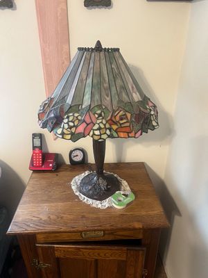 Sale Photo Thumbnail #24: Tiffany-style stained glass table lamp featuring a floral motif border and a detailed bronze-tone base, set on a White Clad oak nightstand.