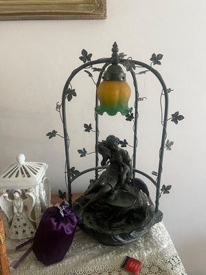 Sale Photo Thumbnail #27: Vintage Art Nouveau style figurative table lamp featuring a dark bronze-tone maiden sculpture under an arched trellis frame with an amber and green tulip-shaped glass shade.