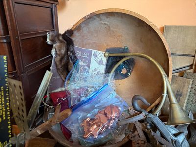 Sale Photo Thumbnail #143: Collection of vintage oddities including a brass french horn, a fur stole piece, a large wooden bowl, copper cookie cutters, and various iron tools.