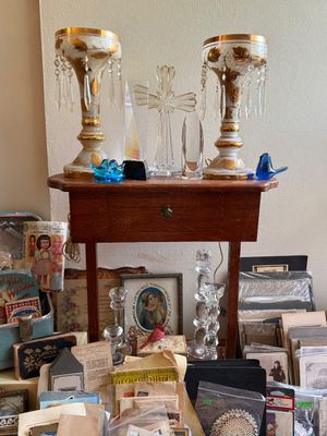 Sale Photo Thumbnail #81: Pair of vintage hand-painted glass luster lamps with gold leaf detail and crystal prisms displayed on a small wooden side table alongside glass collectibles, framed artwork, and ephemera.