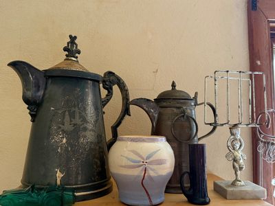 Sale Photo Thumbnail #31: Collection of vintage decorative metalware, ceramics, and glassware including silver-plated coffee pots, a hand-painted ceramic vase, and a cherub-base wire rack.